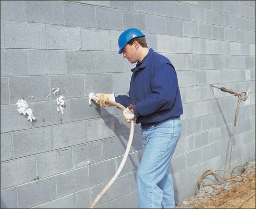 A wall is being filled with CMU foam using the side fill method by drilling 5/8-inch holes.